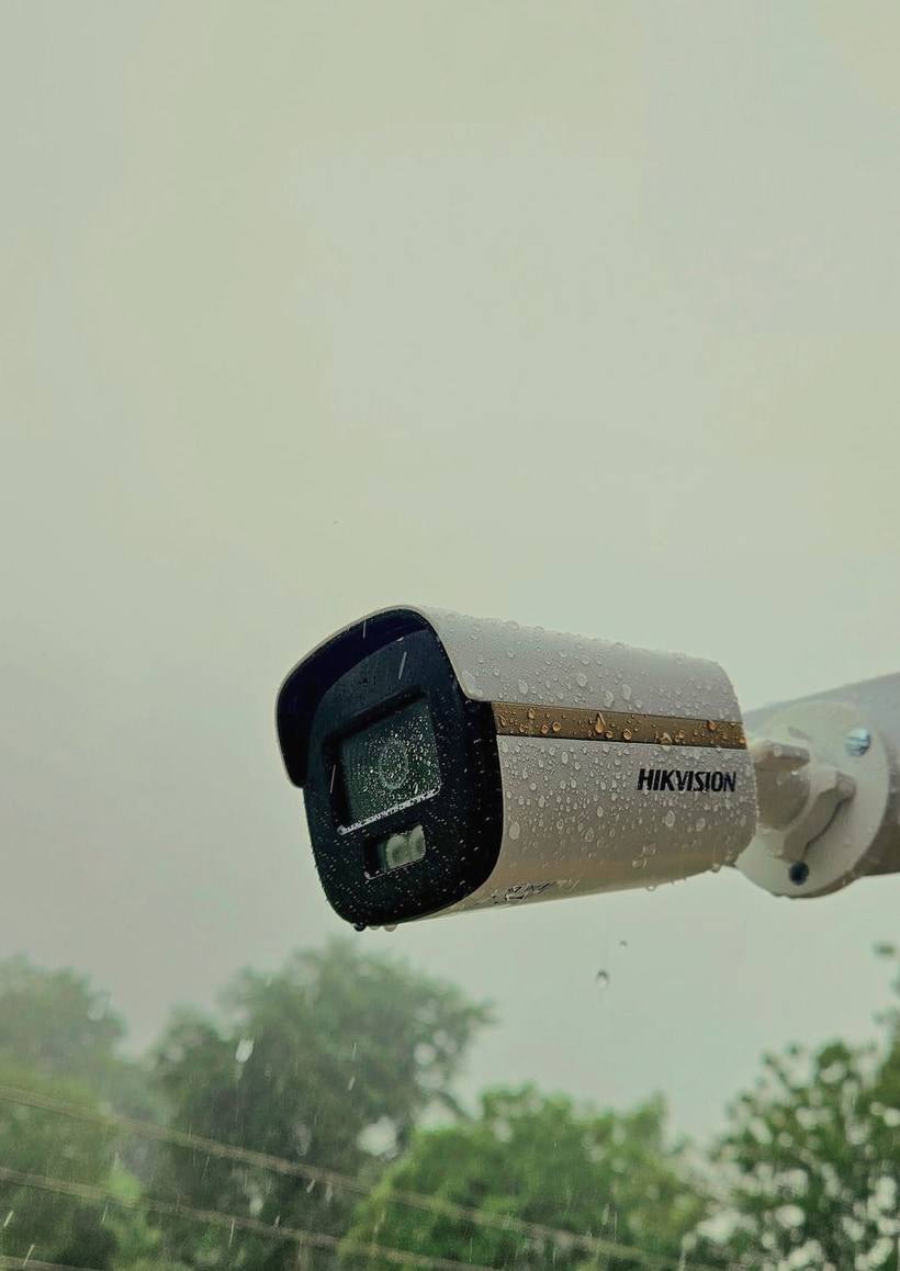 A Hikvision bullet security camera with raindrops on its housing