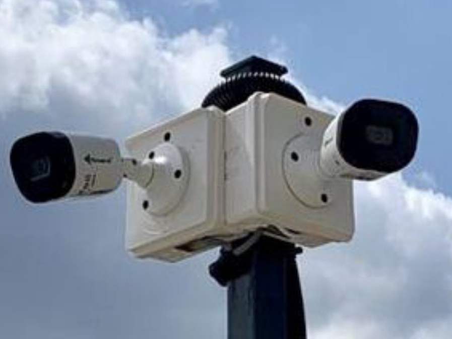 Two bullet CCTV cameras mounted on a pole against the sky