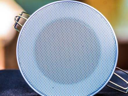 A round ceiling speaker with a white grille