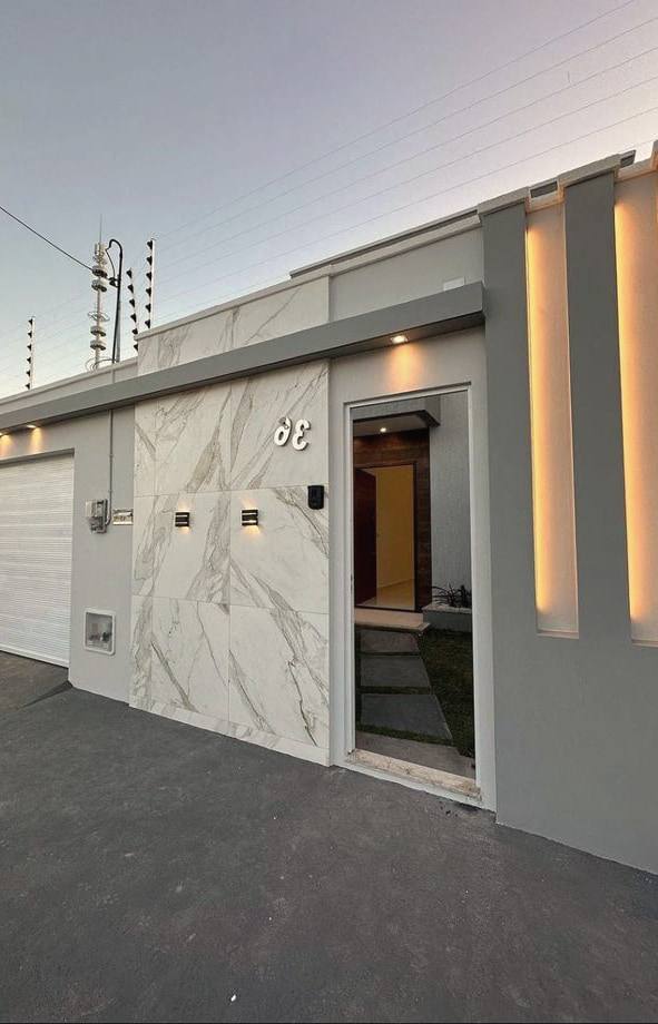 The lit frontage of a house with electric fence wires above the wall