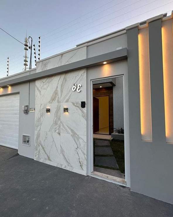 The lit frontage of a house with electric fence wires above the wall