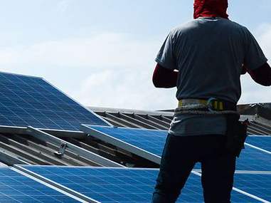An installer standing on a roof covered with solar panels